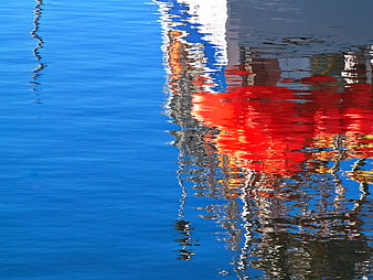 Red boat reflection on blue water with ripples