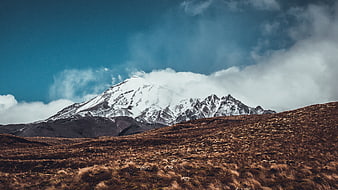 Snow-Capped Mountain Peak Rising Above Brown Grassland