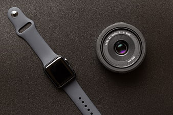Smartwatch and Camera Lens Flat Lay on Dark Textured Surface