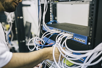 IT Technician Connecting Network Cables in Server Rack
