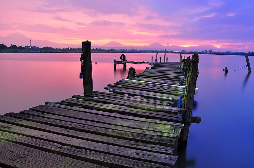 Weathered Wooden Dock at Vibrant Pink and Purple Sunset